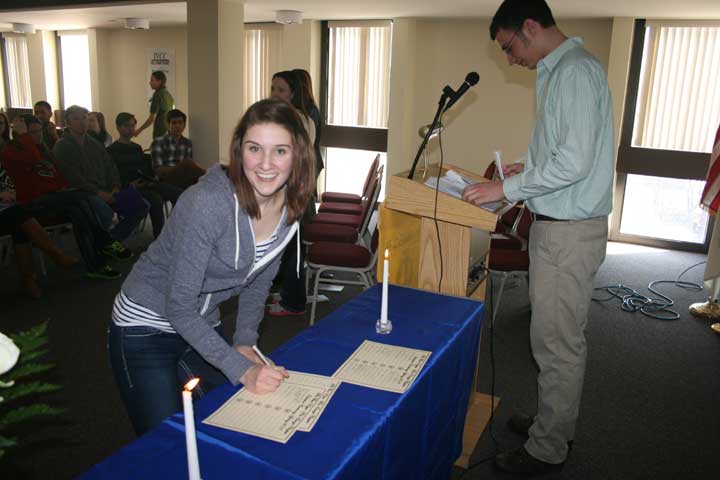Kristina Werner of Streator signs the Phi Theta Kappa log as Braiden Skinner, Rho Omega vice president for membership, introduces new members at the March 28 afternoon induction ceremony.
