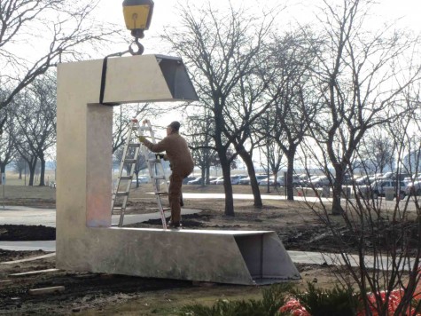 A worker climbs to remove the crane straps off of the final piece of sculpture which will complete the sundial which stands 14 feet tall in front of the CTC building.