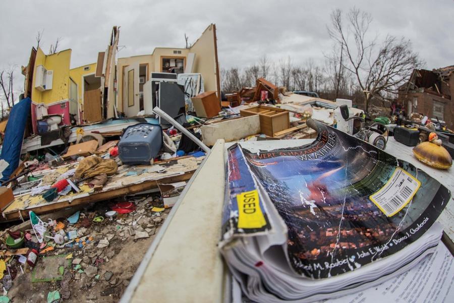 A book on tornadoes and other disasters (top photo) lies outside a damaged house in Naplate after the Feb. 28 storms. 