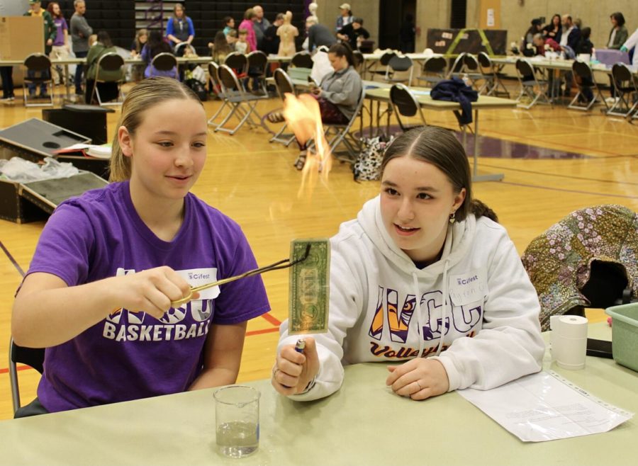 Leah Smudzinski and Payton Giordano lead a demonstration involving lighting a bill on fire without tarnishing the money, on April 21 during the annual Scifest in the IVCC gym.
