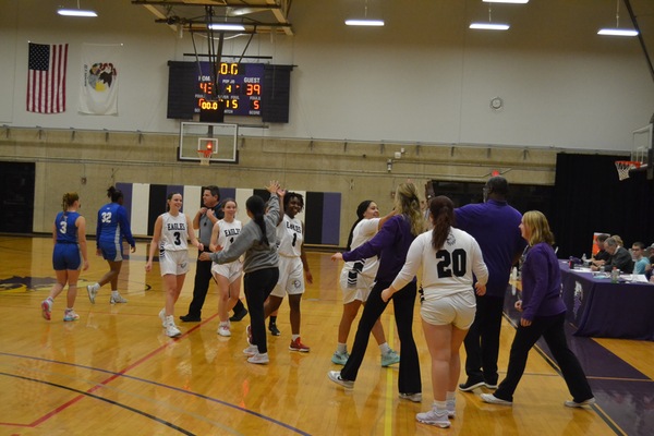 The women's basketball team celebrates their first win of the season vs. Harper College.